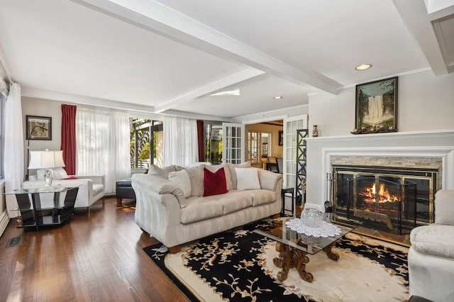 living room featuring beam ceiling, a stone fireplace, and dark hardwood / wood-style flooring