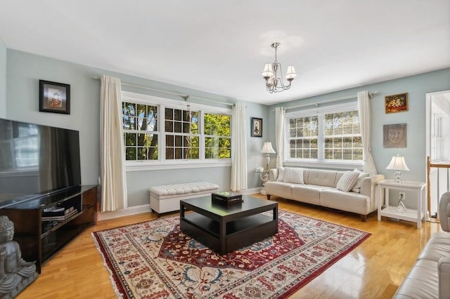 living room with a chandelier, a healthy amount of sunlight, and light hardwood / wood-style flooring