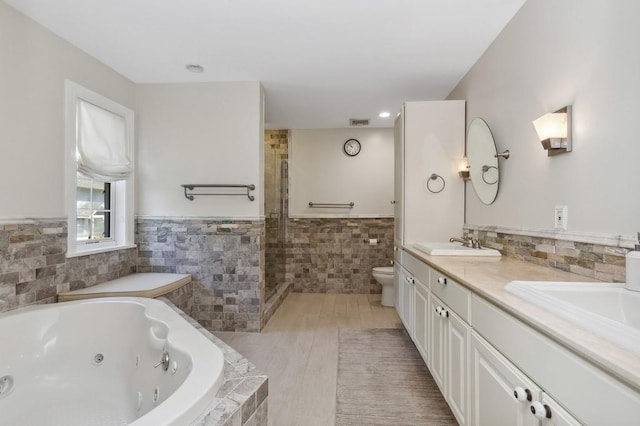 full bathroom featuring hardwood / wood-style floors, vanity, tile walls, and toilet