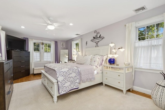 bedroom with multiple windows, ceiling fan, and light hardwood / wood-style flooring