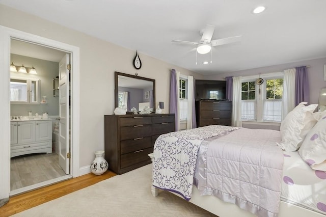 bedroom featuring light wood-type flooring, ceiling fan, and connected bathroom