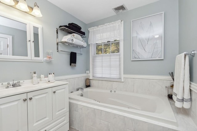 bathroom with vanity and tiled bath