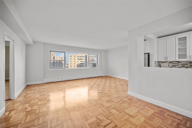 unfurnished room featuring light parquet flooring and a baseboard heating unit