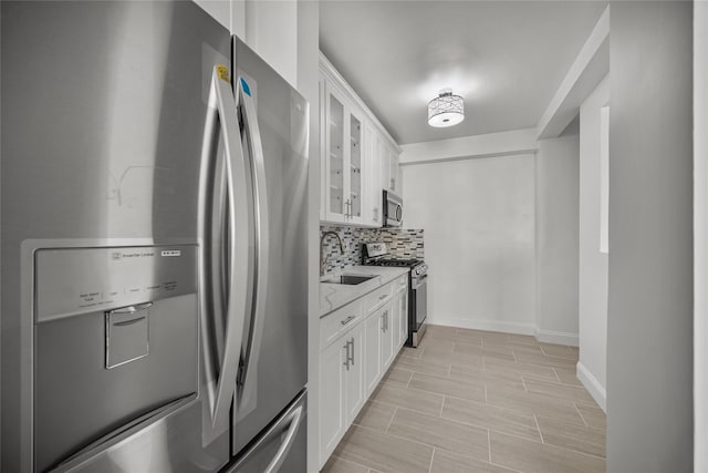 kitchen with light stone countertops, sink, white cabinets, and stainless steel appliances