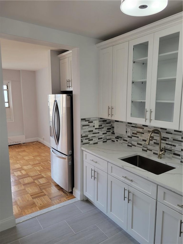 kitchen featuring white cabinets, stainless steel fridge with ice dispenser, light stone counters, and sink