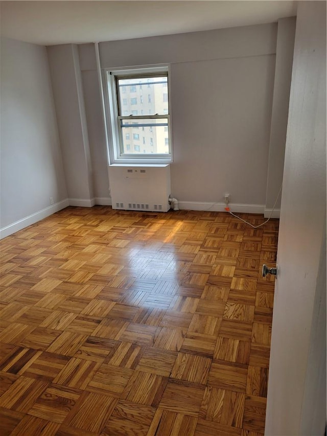 spare room featuring radiator heating unit and light parquet flooring