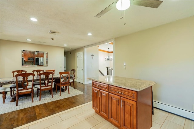 kitchen with a center island, ceiling fan with notable chandelier, light wood-type flooring, a baseboard radiator, and stainless steel appliances