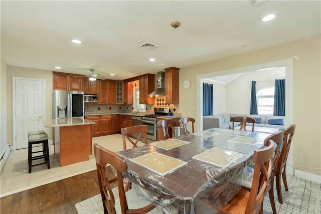 dining space with ceiling fan, light hardwood / wood-style flooring, and sink