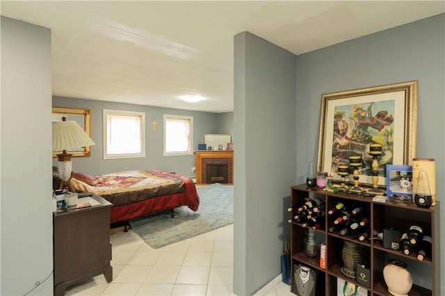 bedroom with light tile patterned floors and a brick fireplace