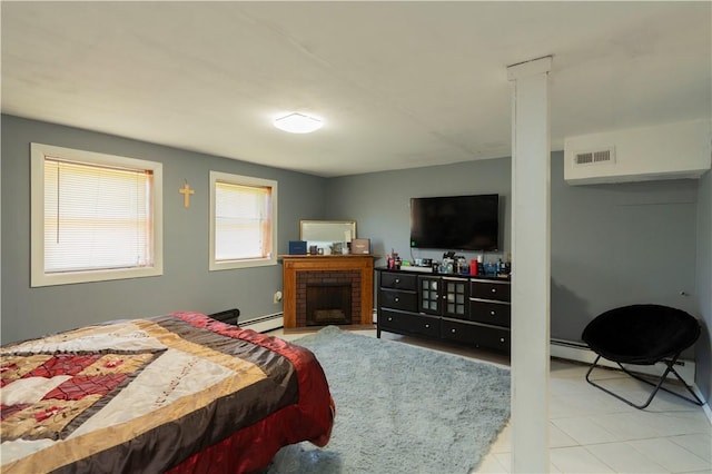 bedroom featuring a fireplace, a baseboard heating unit, and light tile patterned flooring