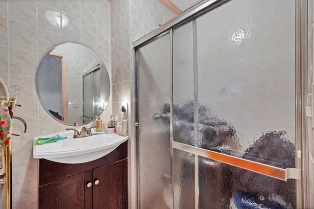 bathroom featuring vanity, a shower with door, and tile walls