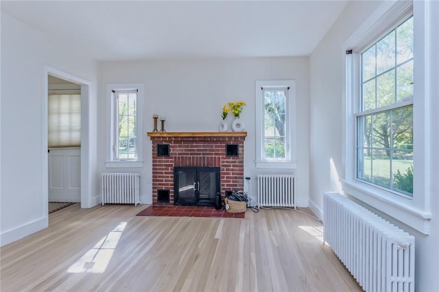 living room with radiator, a fireplace, and light wood-type flooring