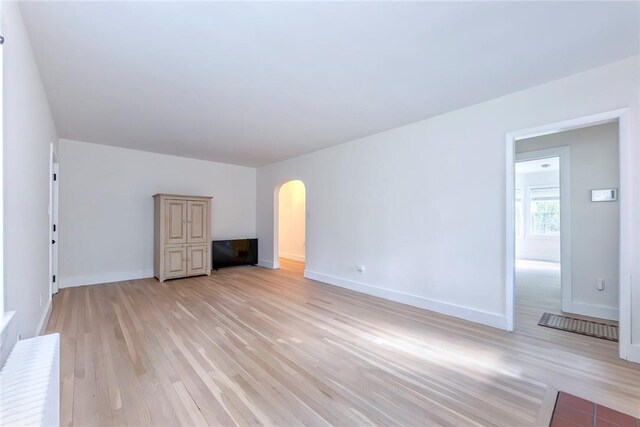 179 Grove St, Tillson, NY 12486 - unfurnished living room with arched walkways, light wood finished floors, and baseboards
