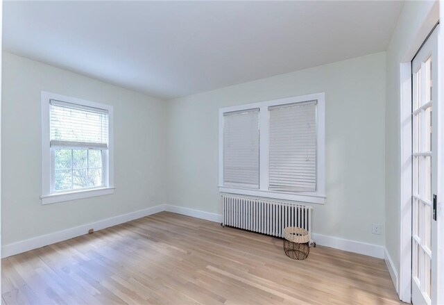 spare room with radiator heating unit and light hardwood / wood-style floors