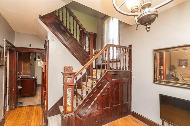 stairs featuring hardwood / wood-style floors and a notable chandelier