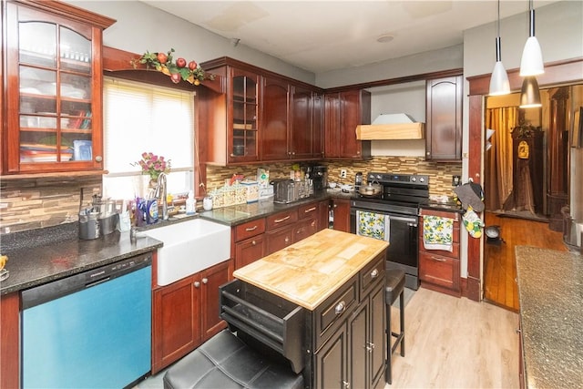 kitchen with backsplash, dark stone counters, stainless steel appliances, light hardwood / wood-style floors, and hanging light fixtures