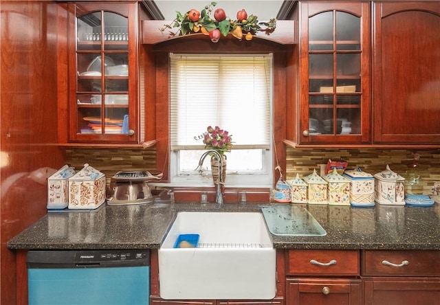 kitchen featuring stainless steel dishwasher, backsplash, sink, and dark stone counters