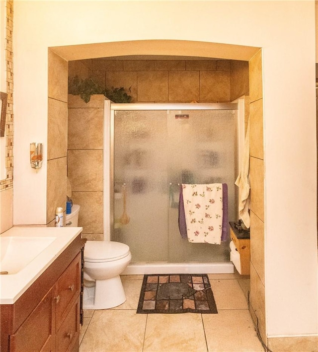 bathroom featuring toilet, vanity, tile patterned floors, and an enclosed shower