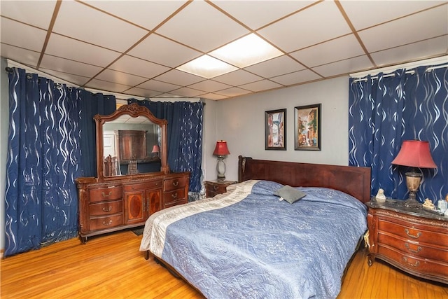 bedroom with a drop ceiling and light hardwood / wood-style floors