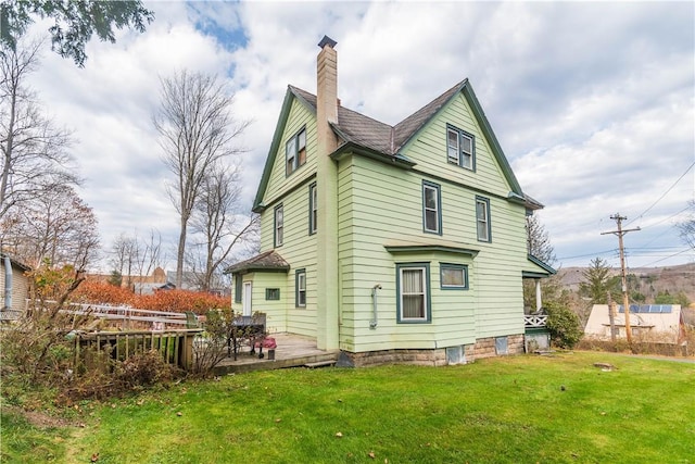 back of house featuring a lawn and a wooden deck