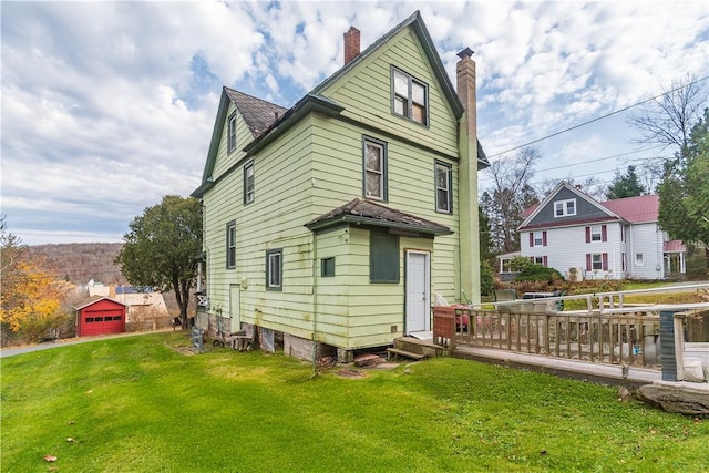 rear view of house featuring a wooden deck and a lawn