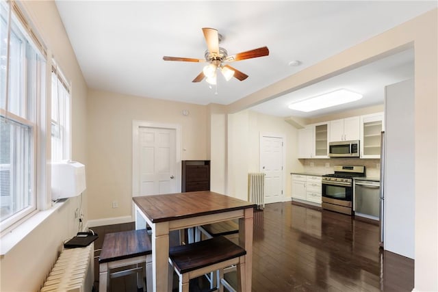 kitchen featuring stainless steel appliances, white cabinetry, a wealth of natural light, and dark wood-type flooring