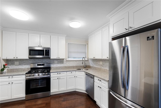 kitchen with sink, dark wood-type flooring, stainless steel appliances, light stone counters, and white cabinets