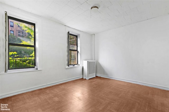 empty room with a healthy amount of sunlight and parquet flooring