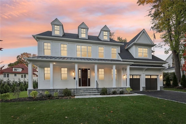 view of front of property with covered porch, a garage, and a lawn