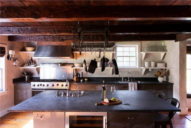 kitchen with sink, wine cooler, beamed ceiling, a breakfast bar, and hardwood / wood-style flooring