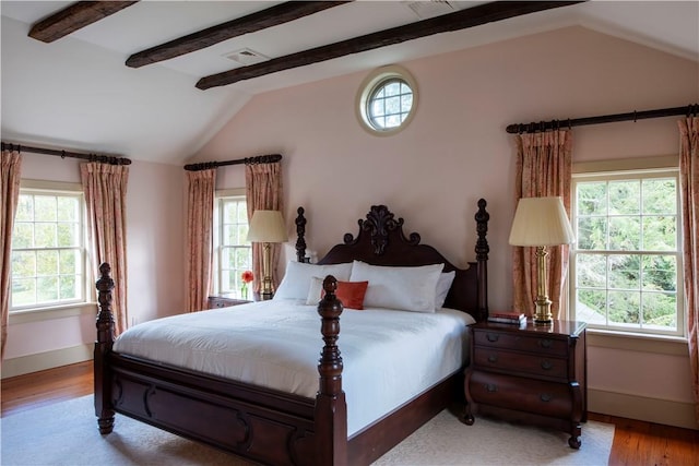 bedroom with lofted ceiling with beams, light hardwood / wood-style flooring, and multiple windows