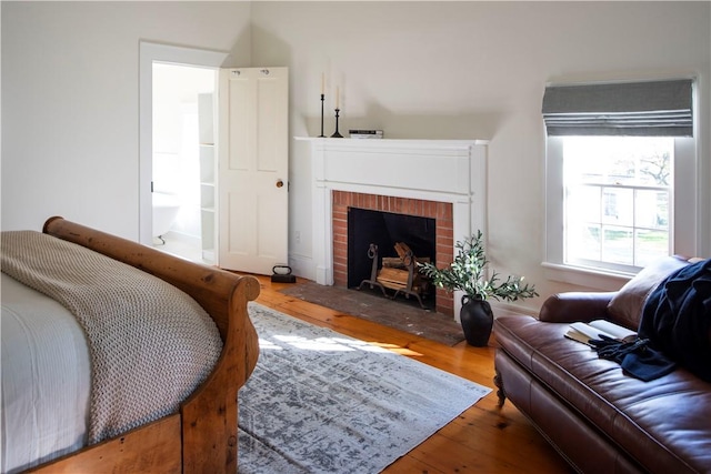 bedroom with hardwood / wood-style flooring, a fireplace, and ensuite bath