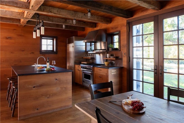 kitchen featuring stainless steel range, sink, exhaust hood, beamed ceiling, and dark hardwood / wood-style floors