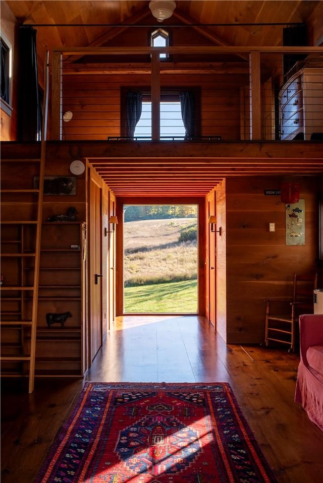 doorway featuring wooden walls, high vaulted ceiling, wooden ceiling, and wood-type flooring