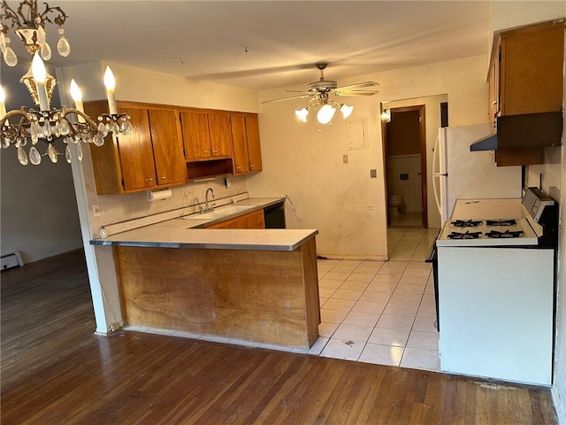 kitchen featuring sink, kitchen peninsula, light hardwood / wood-style floors, white appliances, and ceiling fan with notable chandelier