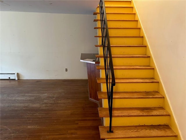 stairs featuring wood-type flooring and a baseboard heating unit