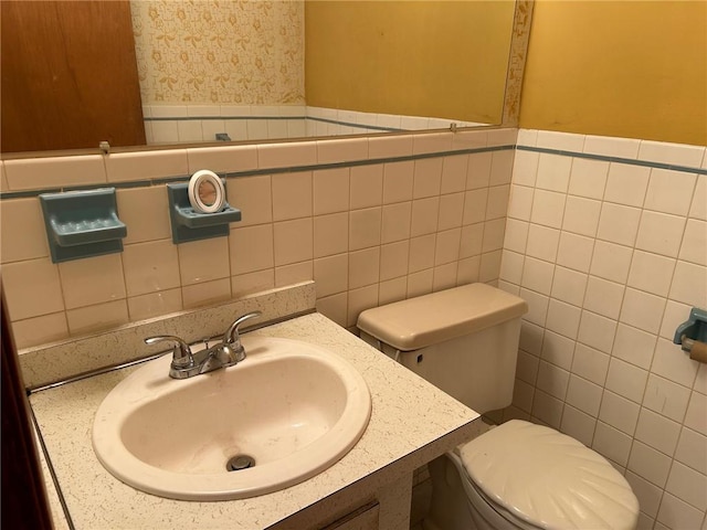 bathroom with vanity, toilet, and tile walls