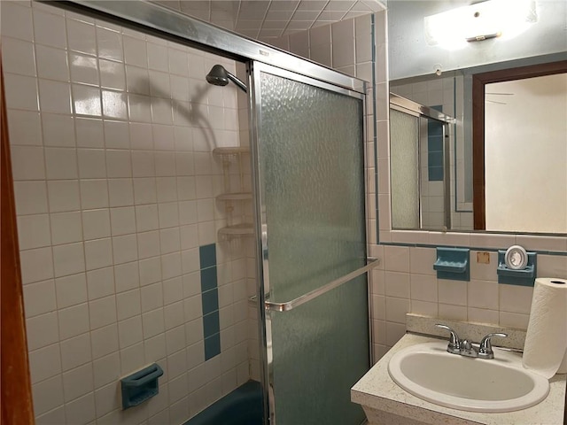 bathroom featuring vanity, enclosed tub / shower combo, and tile walls