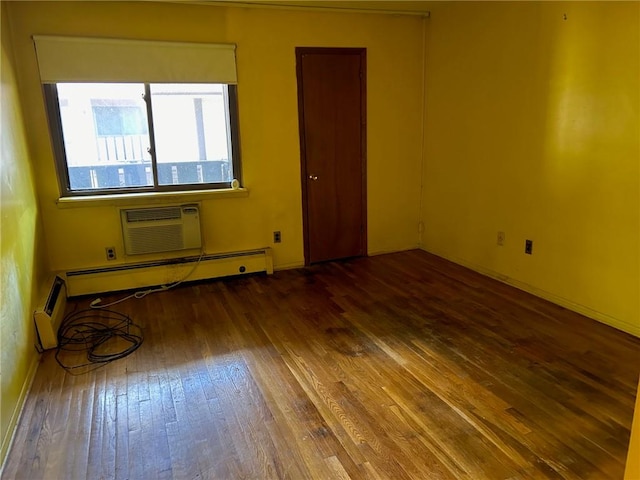 spare room featuring a wall mounted AC, baseboard heating, and dark wood-type flooring