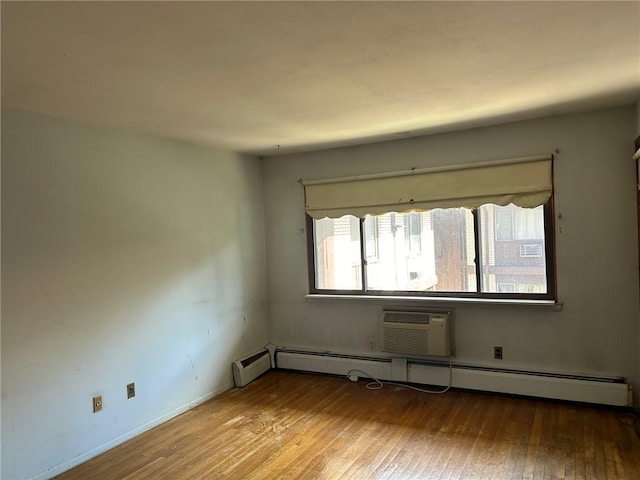 unfurnished room featuring light hardwood / wood-style floors, an AC wall unit, and a baseboard radiator