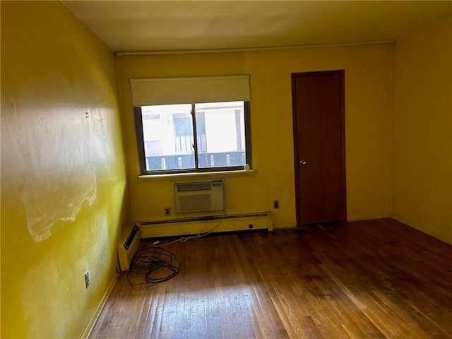 unfurnished room featuring an AC wall unit, dark wood-type flooring, and a baseboard heating unit