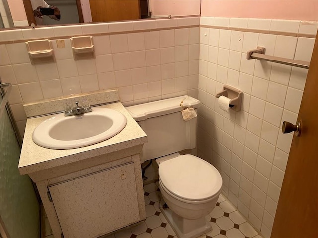 bathroom featuring tile patterned flooring, vanity, tile walls, and toilet