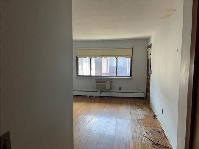 empty room with a wall mounted air conditioner, light wood-type flooring, and a baseboard radiator