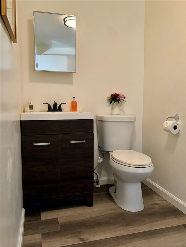 bathroom with wood-type flooring, vanity, and toilet