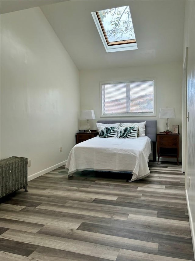 bedroom featuring a skylight, high vaulted ceiling, and wood-type flooring