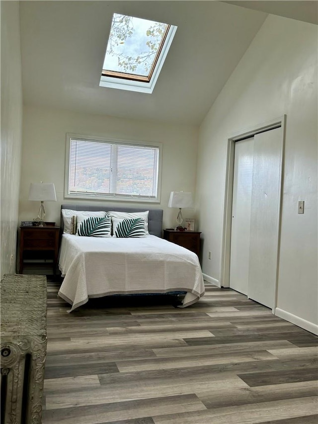 bedroom featuring hardwood / wood-style flooring, high vaulted ceiling, and a skylight