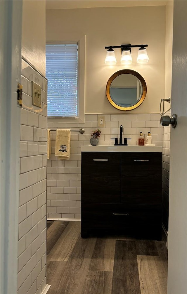 bathroom with hardwood / wood-style floors, vanity, and tile walls