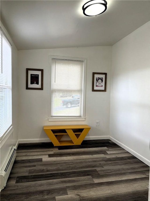 unfurnished room featuring dark hardwood / wood-style flooring, lofted ceiling, and a baseboard radiator