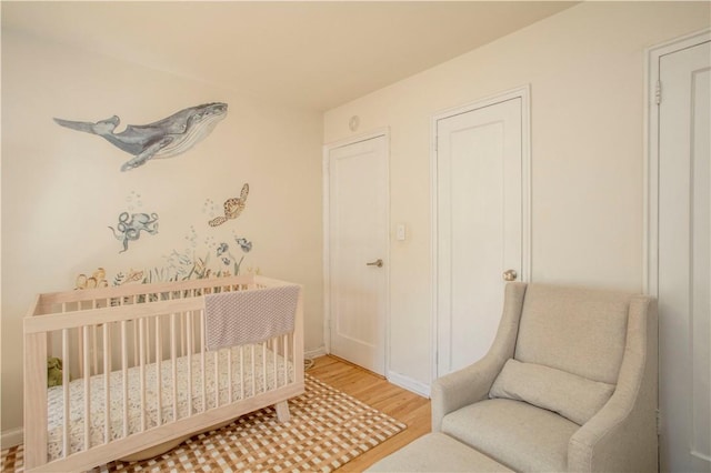 bedroom featuring hardwood / wood-style flooring and a nursery area