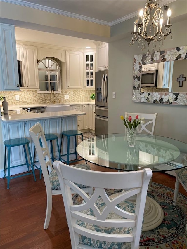 dining room with ornamental molding, dark wood-type flooring, sink, and a chandelier